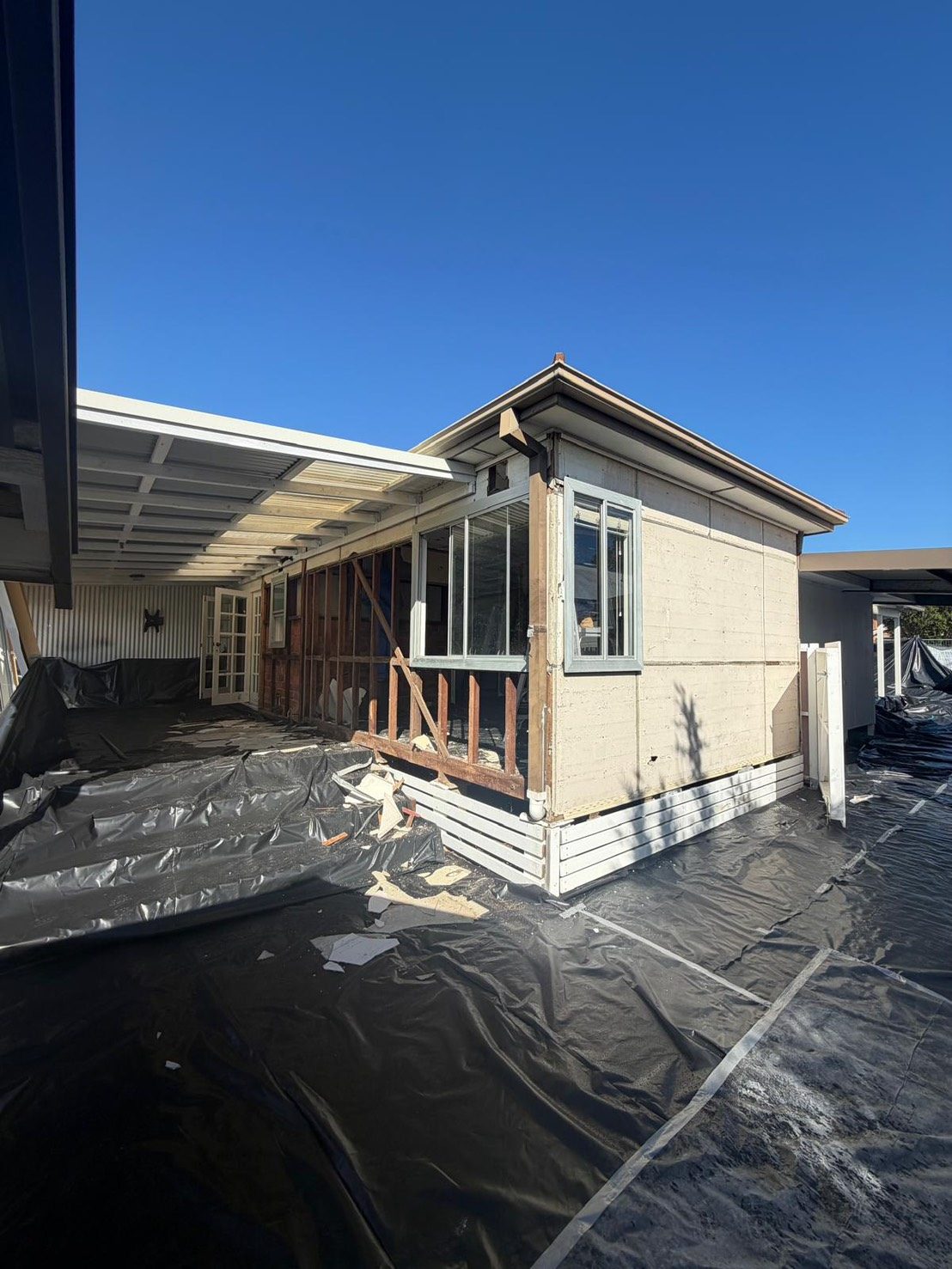 Wide exterior shot of home with asbestos containment sheeting
